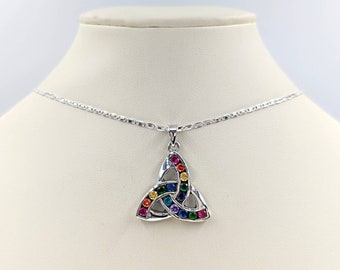 Può includere: Una collana argentata con un ciondolo a nodo celtico. Il ciondolo, di forma triangolare, è impreziosito da pietre preziose multicolori: rosso, arancione, giallo, verde, blu e viola. La catena è sottile e a maglie.