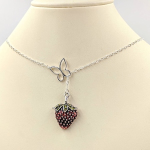 Peut inclure: Un collier en cha&icirc;ne argent avec un pendentif en forme de fraise et un pendentif en forme de papillon. La fraise est rouge avec des feuilles vertes et le papillon est argent&eacute;.