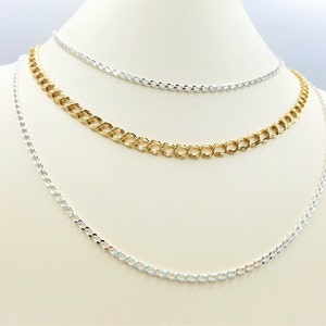 Puede incluir: Tres cadenas de plata de diferentes grosores mostradas en un busto de maniquí blanco.