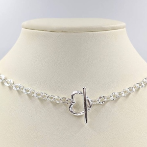 May include: A silver chain necklace with a heart-shaped toggle clasp.