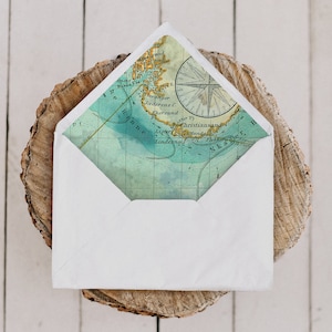 May include: A white envelope with a nautical map liner featuring a compass rose and geographical details in shades of blue, green, and tan. The envelope is open, revealing the map design. The text "ENVELOPE LINERS" is visible.