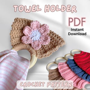 May include: Crocheted towel holder with a flower design. The holder is tan with a pink and white flower. The text "TOWEL HOLDER" and "CROCHET PATTERN" are visible. Several other towel holders in different colors are also shown.