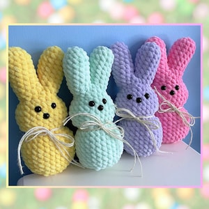 May include: Four crocheted bunny plushies in yellow, light blue, purple, and pink. The bunnies are all sitting on a light blue surface.