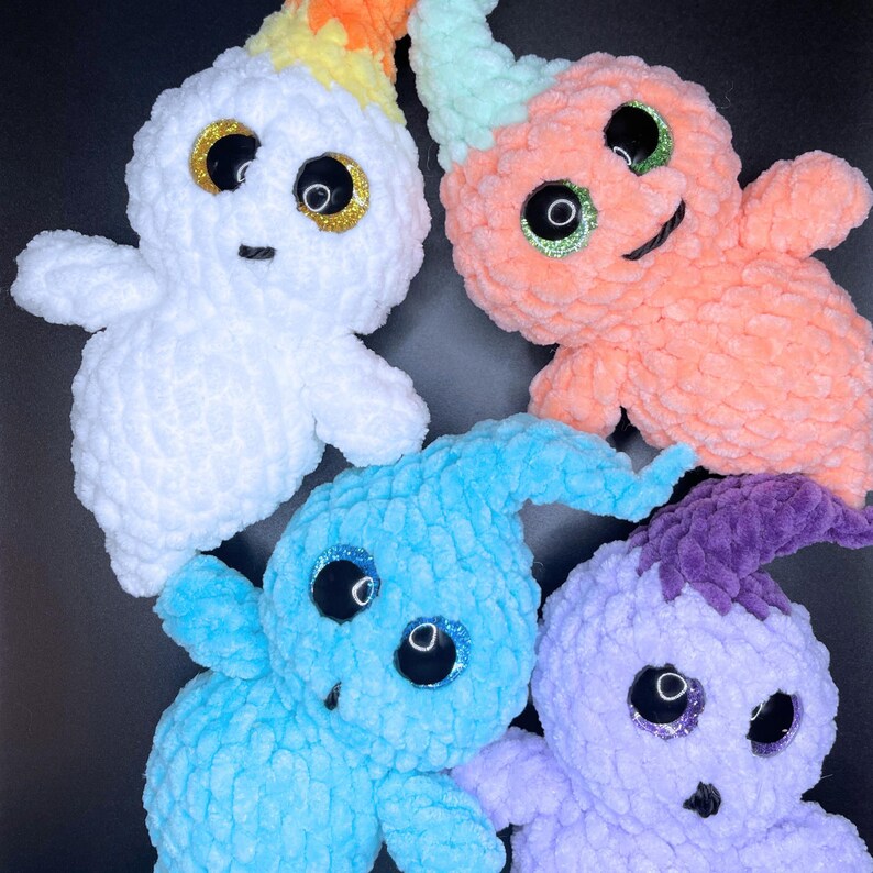 May include: Four crocheted ghost plushies with googly eyes. The ghosts are white, light blue, light pink, and orange.