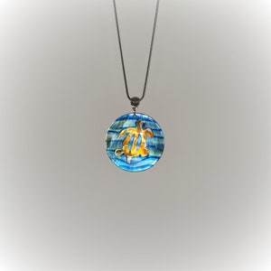 May include: A silver chain necklace with a round blue and gold pendant featuring a sea turtle design.