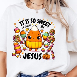 May include: White t-shirt with a cartoon candy corn holding lollipops and the text "It is so sweet to trust in Jesus".