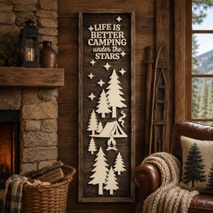 May include: A tall, rectangular wooden wall sign with a dark brown frame and a dark wood background. It features light-coloured, laser-cut wooden silhouettes of pine trees, a tent, a campfire, and stars, with the text LIFE IS BETTER CAMPING under the STARS.