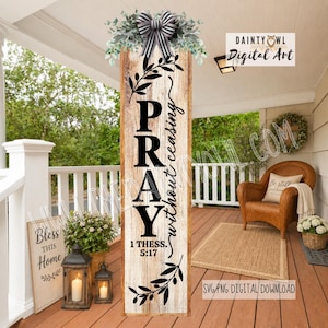 May include: A vertical wooden porch sign with a weathered light brown finish, featuring the black text PRAY without ceasing 1 THESS. 5:17. The sign is decorated with black leafy vine illustrations and topped with a black and white striped bow.