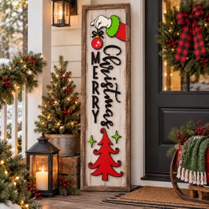 Peut inclure: Un grand panneau de porche rectangulaire en bois avec une finition blanche vieillie. Il présente le texte noir Merry Christmas, un sapin de Noël rouge et une main de dessin animé à fourrure verte tenant une boule rouge.