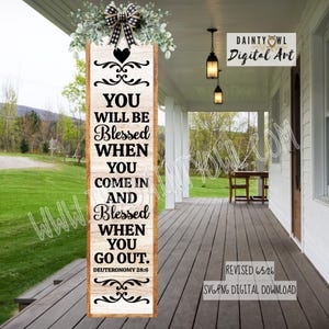 May include: A vertical wooden sign with a light wood grain finish featuring black text that reads: YOU WILL BE Blessed WHEN YOU COME IN AND Blessed WHEN YOU GO OUT. DEUTERONOMY 28:6. The sign is topped with a black and white plaid bow and greenery.