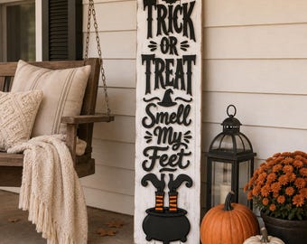 May include: A tall, rectangular white wooden sign with distressed edges featuring black raised lettering that reads "TRICK OR TREAT SMELL MY FEET". The design includes a black bat, a witch hat, and a black cauldron with striped socks sticking out.