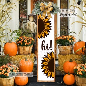 Puede incluir: Un letrero vertical de madera con un diseño de girasol y la palabra "hi!" en negro. El letrero está adornado con un lazo y vegetación. Calabazas, balas de heno y cestas de flores crean un tema otoñal.