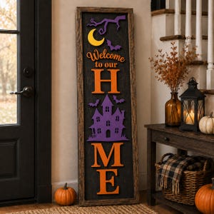 May include: A tall rectangular wooden sign with a dark textured background featuring the text Welcome to our HOME in orange letters. The design includes a yellow crescent moon, purple bats, a purple haunted house, and a purple tree branch.