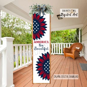 May include: A wooden sign with a patriotic theme. It features two red and blue sunflower designs with white stars, and the words "AMERICA the Beautiful." The sign is decorated with greenery and a plaid bow.