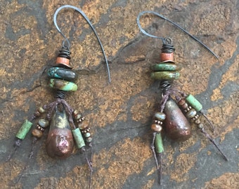 May include: A pair of dangle earrings with a teardrop-shaped pendant, turquoise, copper, and brown beads, and a silver wire hook.