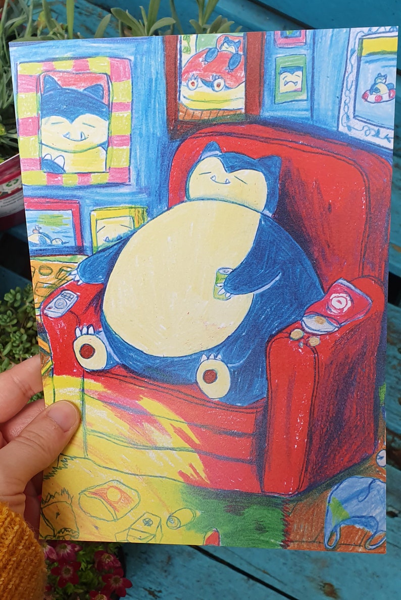 Op de afbeelding: Een kleurrijke illustratie van een stripfiguur, Snorlax, ontspannen in een rode fauteuil. Het personage is blauw en cr&egrave;me, houdt een blikje vast, met snacks en een afstandsbediening in de buurt. Kunstwerk toont ingelijste foto's aan de muur.