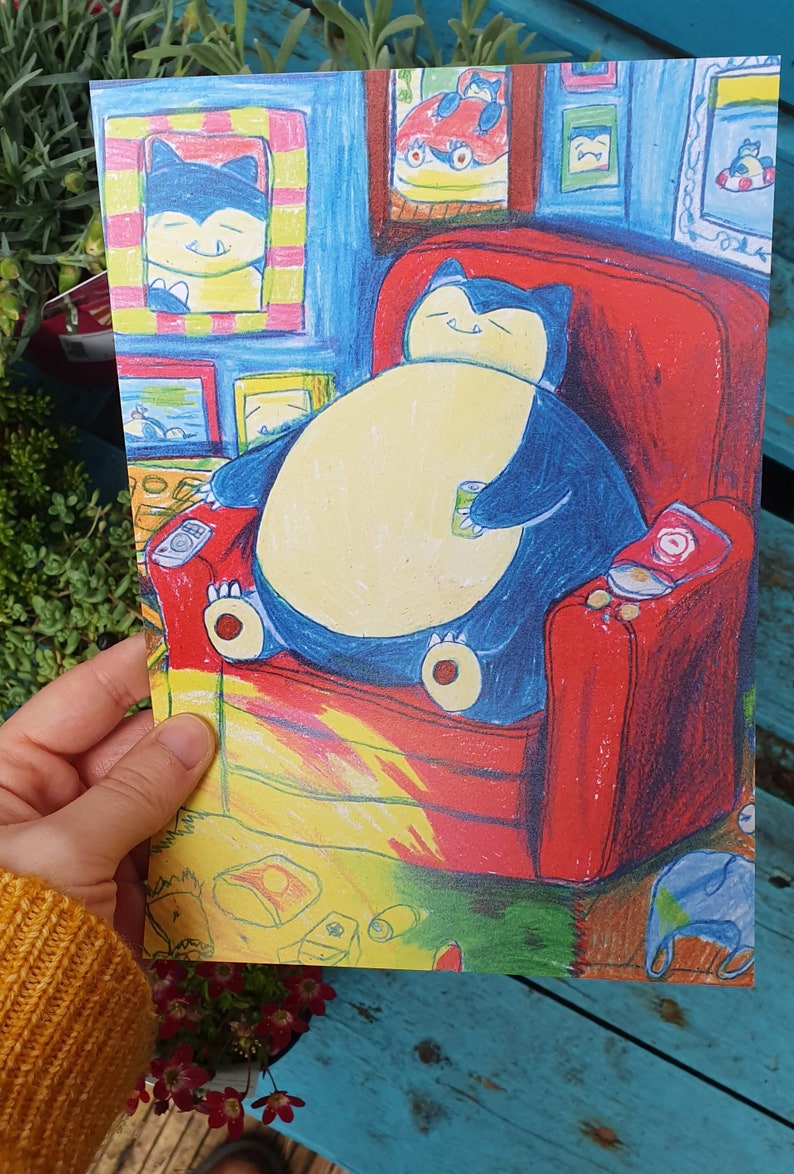 Op de afbeelding: Kleurrijke illustratie van een Snorlax-personage dat ontspant in een rode fauteuil, met een blikje in zijn hand. Het kunstwerk toont ingelijste foto's aan de muur en een gele en bruine vloer. De sfeer is gezellig en cartoonachtig.