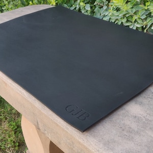 Puede incluir: Estera de yoga negra con las letras "GJB" en relieve en la esquina inferior derecha.