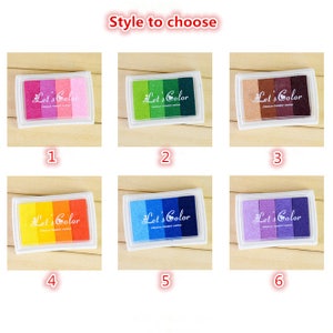 May include: Six different colored ink pads with the text "Let's Color" on each. The ink pads are arranged in two rows of three. The colors are pink, green, brown, orange, blue, and purple.