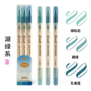 May include: A set of twin-tip brush markers in shades of teal and blue. The markers are labeled "Brush Twin Marker" and come in a clear plastic package. The image also shows color swatches and Chinese text.