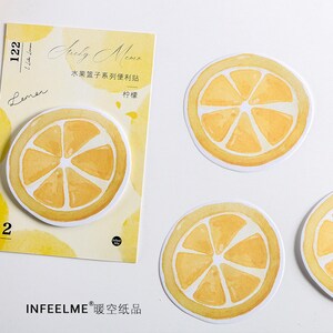 May include: A set of four yellow lemon-shaped sticky notes with watercolor designs. The notes are packaged on a card with the text "Sticky Memo" and "Lemen" in black lettering.