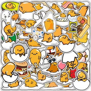 Puede incluir: Una colección de pegatinas coloridas con el personaje de dibujos animados Gudetama. Las pegatinas representan a Gudetama en varias poses, incluso dentro de un huevo, en un plato y con accesorios. Las pegatinas son amarillas, blancas y marrones.