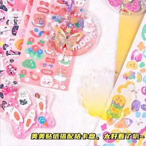 May include: A set of colourful, glittery resin charms with cute cartoon characters and designs. The charms are decorated with stickers featuring butterflies, flowers, and the word "moon".