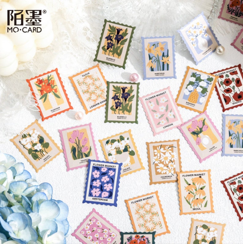 May include: A set of 18 colorful floral stickers with a vintage stamp design. Each sticker features a different flower and the name of a city, such as Amsterdam, London, and Seoul. The stickers are perfect for adding a touch of whimsy to journals, planners, and other paper crafts.