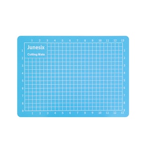 May include: A light blue self-healing cutting mat with a grid pattern and numbers 1 through 13 along the top and bottom edges. The text "Junesix Cutting Mats" is printed in the top left corner.