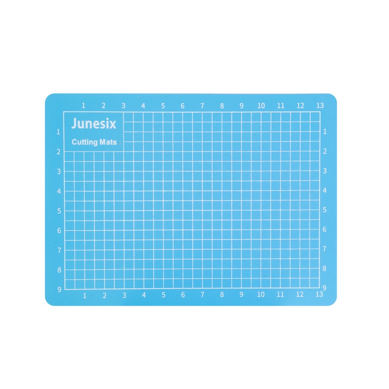May include: A light blue self-healing cutting mat with a grid pattern and numbers 1 through 13 along the top and bottom edges. The text "Junesix Cutting Mats" is printed in the top left corner.