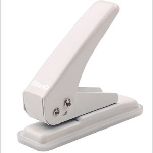 May include: White metal hole punch with a lever and a base. The hole punch is labeled "Office".