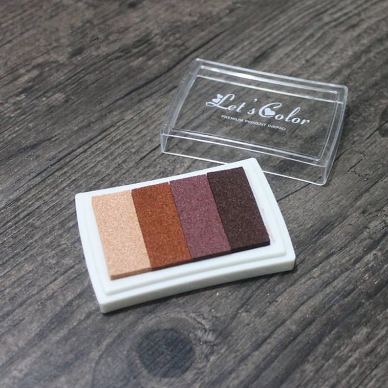 May include: A white ink pad with four color ink pads: beige, brown, burgundy, and dark brown. The ink pad is labeled "Let's Color Premium Pigment Inkpad".