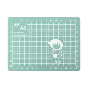 May include: A green self-healing cutting mat with a grid pattern and numbers 1 through 13 along the top and bottom edges. The mat is labeled "唐氏 A6 姚工匠DIY手工 Cutting Mat".