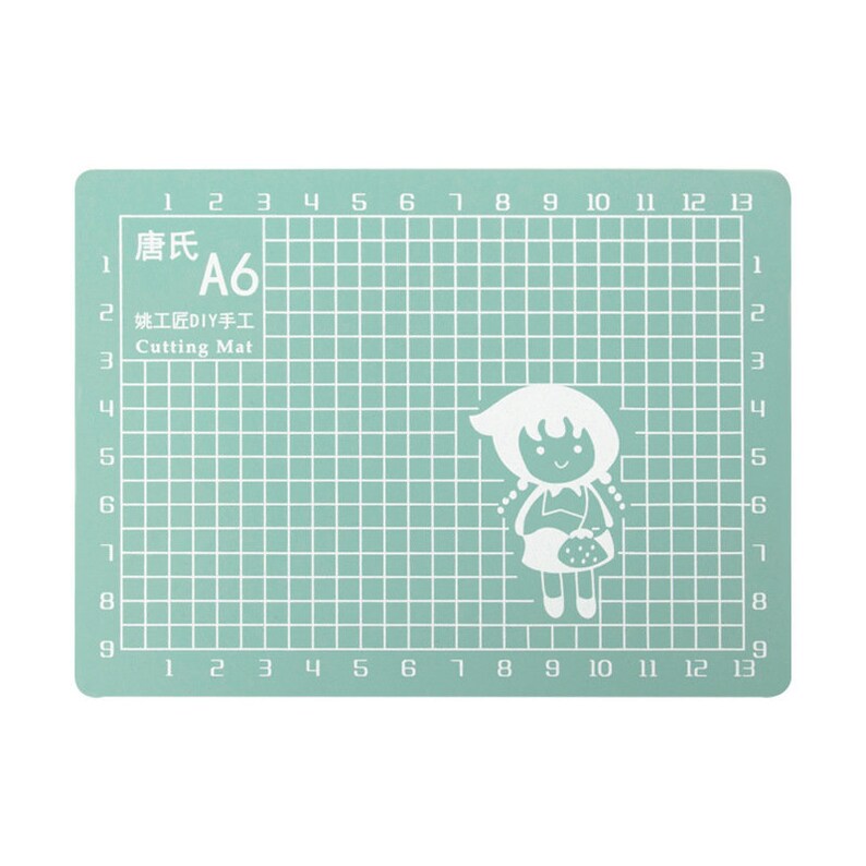 May include: A green self-healing cutting mat with a grid pattern and numbers 1 through 13 along the top and bottom edges. The mat is labeled "唐氏 A6 姚工匠DIY手工 Cutting Mat".