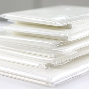 Op de afbeelding: Een stapel witte vellen papier verpakt in doorzichtige plastic verpakking. De vellen zijn glad en lijken blanco te zijn.