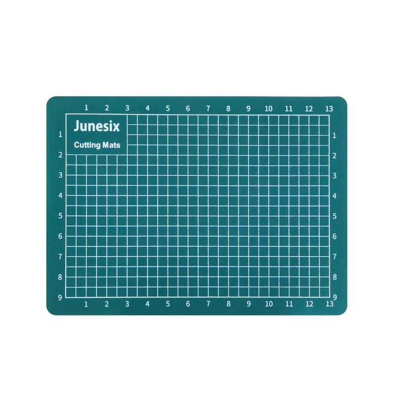 May include: A green self-healing cutting mat with a grid pattern and numbered rows and columns. The mat is labeled "Junesix Cutting Mats".
