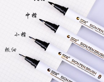 May include: Four black brush pens with white barrels and gold lettering. The pens are labeled "STA SIGN PEN BRUSH" and have different sized tips. The text "大楷", "中楷", "小楷", and "极细" is written in black ink on a white sheet of paper.