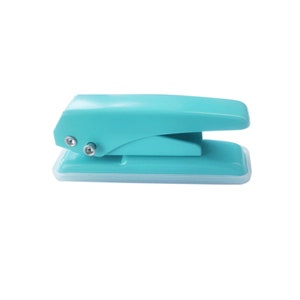 May include: A turquoise blue handheld paper punch with a white base. The punch has a lever on top and two metal holes for punching.