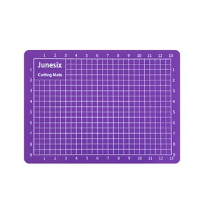 May include: Purple self-healing cutting mat with a grid pattern and numbered rows and columns. The mat is labeled "Junesix Cutting Mats".
