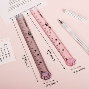 May include: Two pink plastic rulers with paw print designs. Each ruler is 17 inches long and has a paw print at the end. The rulers are 2.3 inches wide.