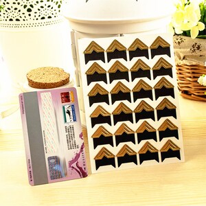 May include: A sheet of gold and black corner stickers for scrapbooking or photo albums. The stickers are arranged in rows and columns on a white background.