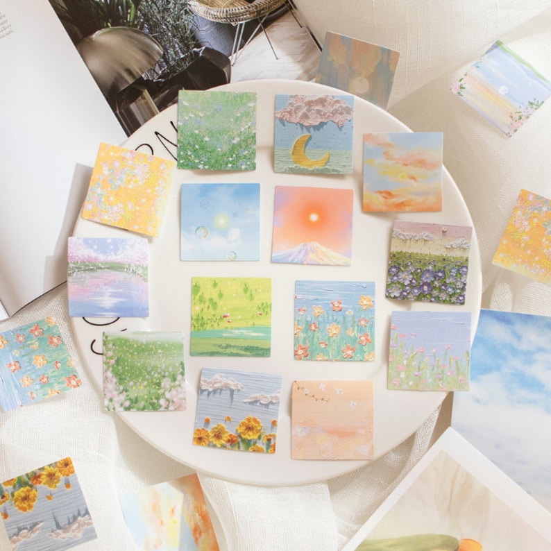 May include: A set of 16 colorful square stickers featuring various nature scenes. The stickers depict landscapes with flowers, clouds, mountains, and water. The stickers are perfect for adding a touch of whimsy to journals, planners, and other craft projects.