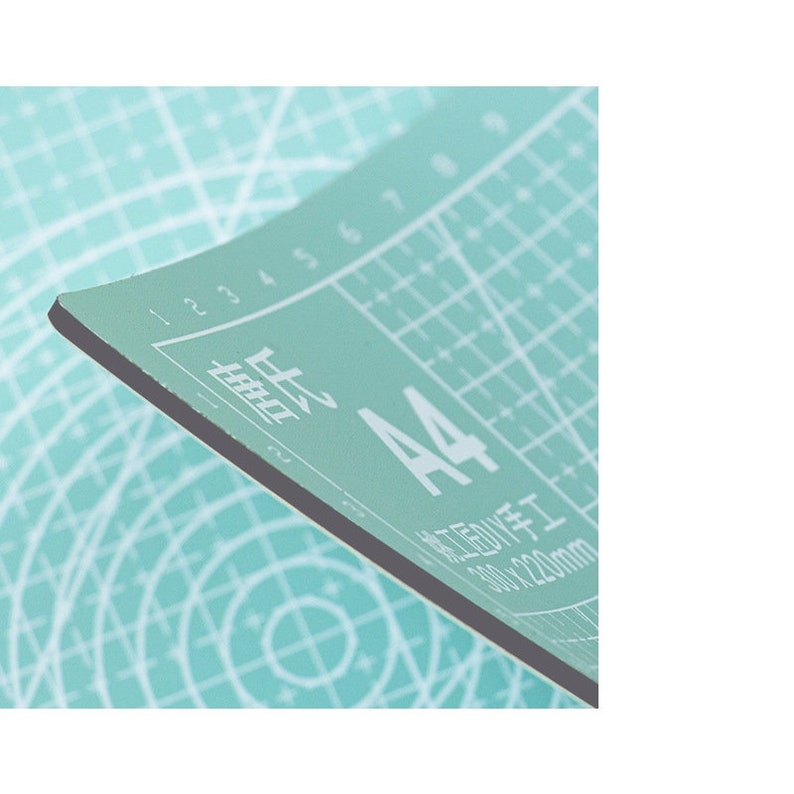 May include: A light green cutting mat with a grid pattern and the text "A4 210 x 297mm" printed on it.