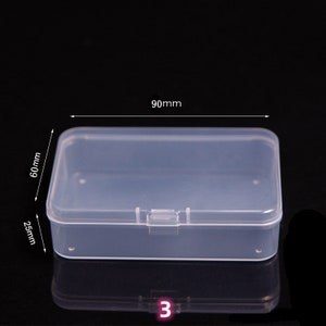 May include: A clear plastic storage box with a hinged lid. The box measures 90mm by 60mm by 25mm.