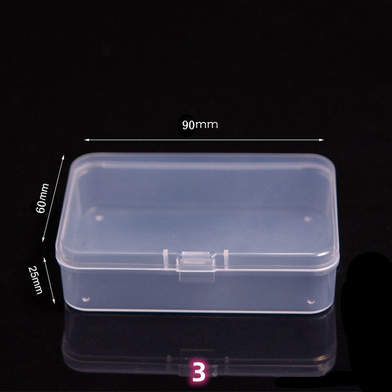 May include: A clear plastic storage box with a hinged lid. The box measures 90mm by 60mm by 25mm.