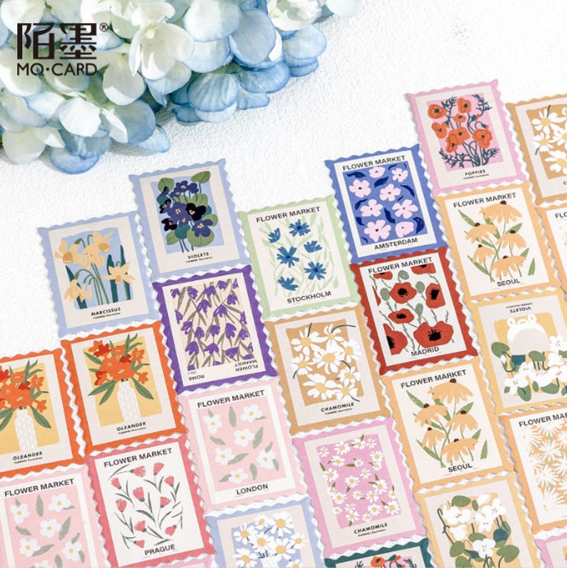 May include: A set of 20 colorful stickers featuring various flowers and the text "FLOWER MARKET" with the city name below. The stickers are designed to look like postage stamps with a scalloped edge.