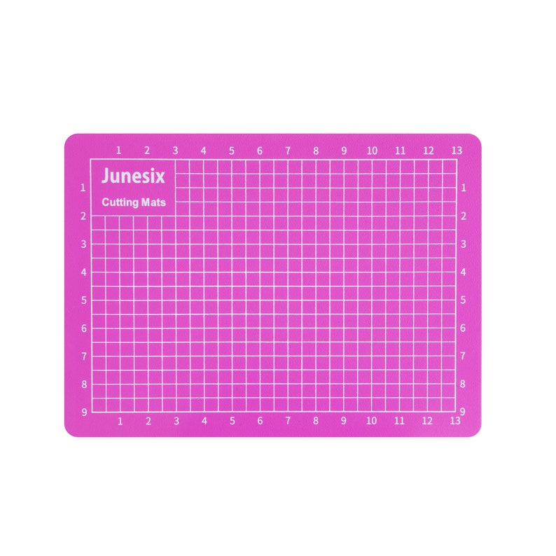 May include: A pink self-healing cutting mat with a grid pattern and numbers 1 through 13 along the top and bottom edges. The mat is labeled "Junesix Cutting Mats".