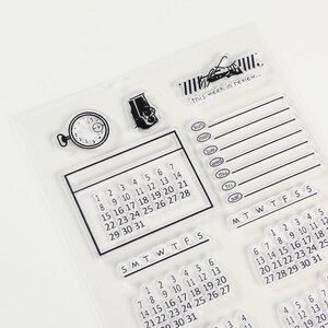 Pu&ograve; includere: Set di timbri trasparenti con vari elementi di calendario e pianificazione. Include una griglia del calendario, un banner di revisione settimanale, un orologio e un'icona della fotocamera. Il testo "this week in review..." &egrave; visibile.