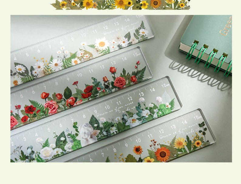 May include: Four clear plastic rulers with floral designs. Each ruler is 15 inches long and features pressed flowers and greenery. The rulers are labeled with numbers from 1 to 15.