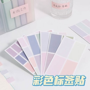 May include: A collection of pastel-colored rectangular stickers with a geometric design. The stickers are arranged in a fan shape, showcasing shades of pink, purple, blue, and green. The text "Colorful Labels" is visible in the bottom right corner.